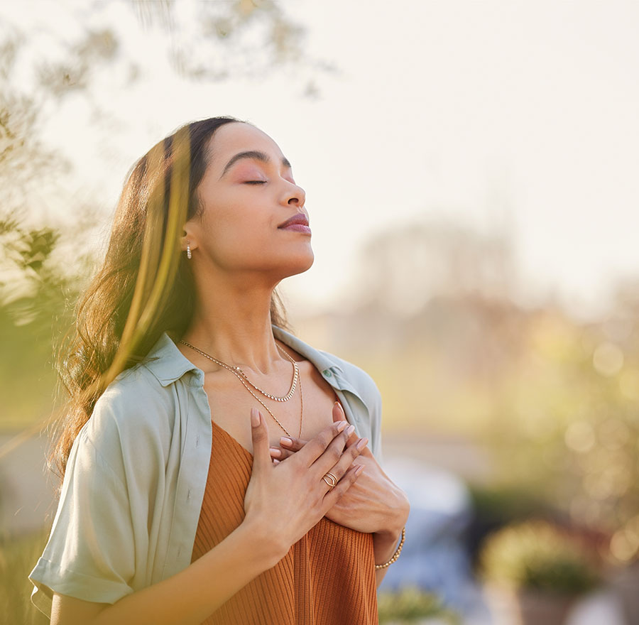 woman with eyes closed with hands on heart, outside